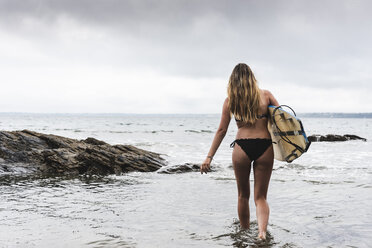 Junge Frau mit Surfbrett beim Stretching am Strand - UUF15049