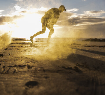 Man doing movement training at the beach with colorful smoke at sunset - UUF15056