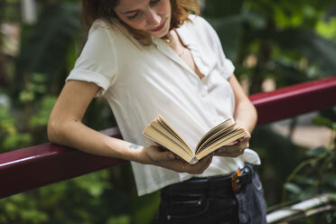 Junge Frau im Gewächshaus, die ein Buch liest - KKAF01672