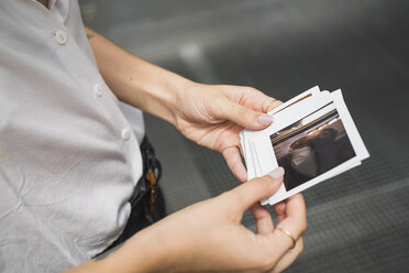 Junge Frau mit Sofortfotos in der Hand - KKAF01676