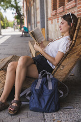 Young woman sight seeing in Madrid, taking a break, reading book - KKAF01686