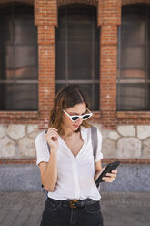 Young woman sight seeing in Madrid, using smartphone - KKAF01690