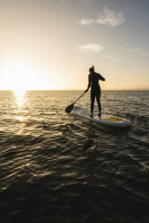 Junge Frau Stand Up Paddle Surfing bei Sonnenuntergang - UUF15070