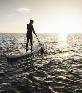 Junge Frau Stand Up Paddle Surfing bei Sonnenuntergang - UUF15071