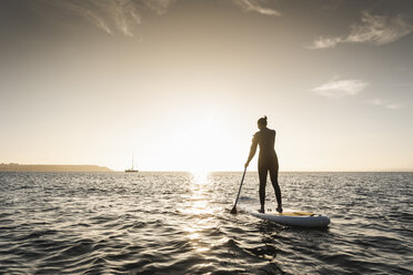Junge Frau Stand Up Paddle Surfing bei Sonnenuntergang - UUF15072