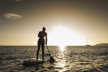 Junge Frau Stand Up Paddle Surfing bei Sonnenuntergang - UUF15073