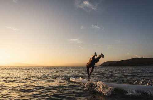 Junger Mann auf Paddleboard bei Sonnenuntergang - UUF15088