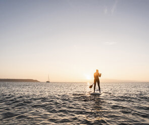 Junge Frau Stand Up Paddle Surfing bei Sonnenuntergang - UUF15092