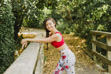 Young woman smiling during break, after practicing Pilates in an urban park - NMSF00243