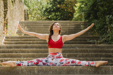 Young woman practicing Pilates in an urban park, spagat on steps - NMSF00247