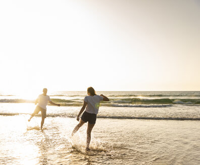 Junges Paar, das sich am Strand vergnügt und im Meer plantscht - UUF15102