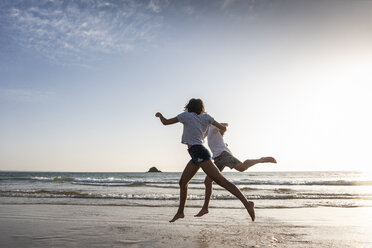 Young couple having fun on the beach, running and jumping at the sea - UUF15107