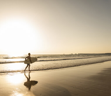 Junger Mann läuft am Strand, trägt Surfbrett - UUF15113