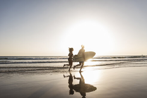 Junges Paar läuft am Strand, trägt Surfbrett - UUF15120