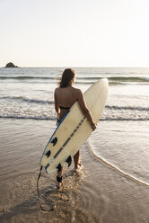 Junge Frau geht im Wasser, trägt Surfbrett - UUF15131