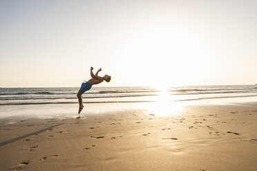 Young man doing somersaults on the beach - UUF15133