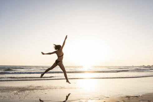 Junge Frau springt vor Freude am Strand - UUF15143