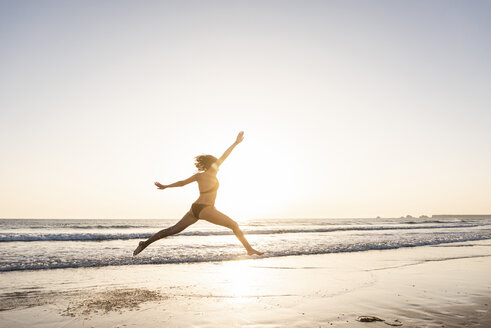 Junge Frau springt vor Freude am Strand - UUF15144