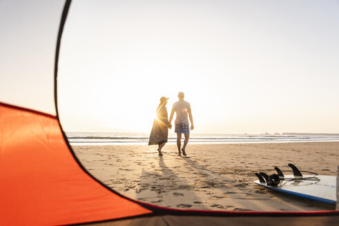 Romantisches Paar, das am Strand zeltet und bei Sonnenuntergang einen Strandspaziergang macht - UUF15148