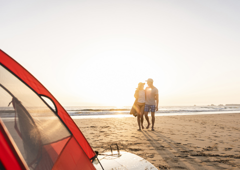 Romantic couple camping on the beach, doing a beach stroll at sunset stock photo