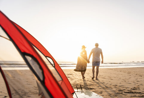 Romantisches Paar, das am Strand zeltet und bei Sonnenuntergang einen Strandspaziergang macht - UUF15152