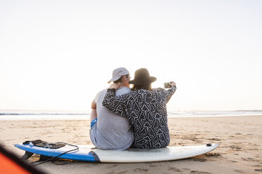 Couple camping on the beach, taking smartphone selfies - UUF15155