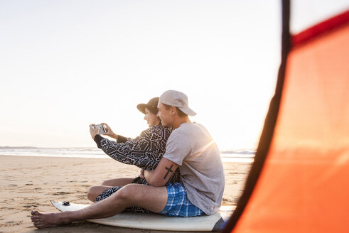 Pärchen zeltet am Strand und macht Smartphone-Selfies - UUF15156