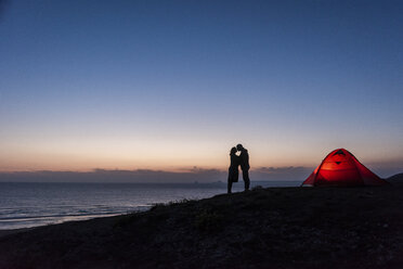 Romantisches Paar beim Zelten am Strand, küssend in der Dämmerung - UUF15170