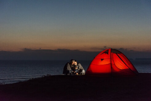 Romantisches Paar beim Zelten am Strand, mit Smartphone - UUF15172
