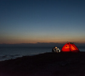 Romantisches Paar beim Zelten am Strand, mit Smartphone - UUF15173