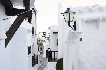 Spain, Menorca, Binibequer, back view of woman walking in an alley - IGGF00585