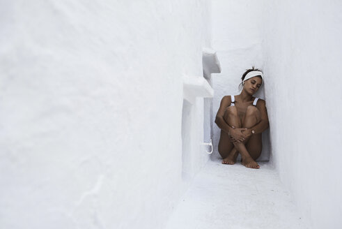 Young woman sitting on the ground in a wall niche - IGGF00602