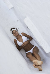 Junge Frau im weißen Bikini in einer Mauernische liegend, Ansicht von oben - IGGF00604