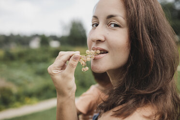 Porträt einer Frau, die weiße Johannisbeeren isst - KMKF00546