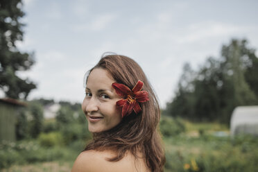 Portrait of smiling woman with flower in her hair - KMKF00547