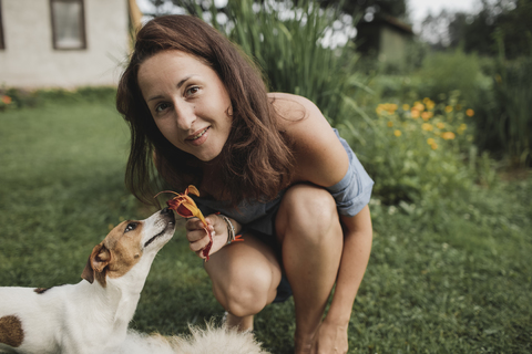 Porträt einer lächelnden Frau mit Jack Russel Terrier im Garten, lizenzfreies Stockfoto