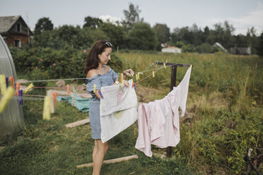 Woman hanging up laundry in garden - KMKF00556
