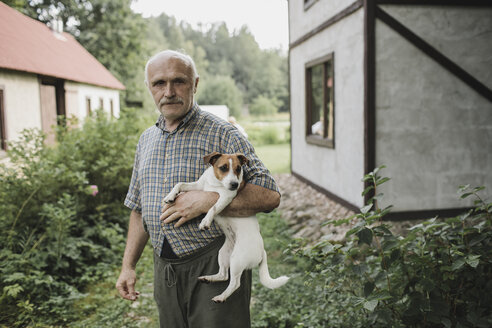 Porträt eines älteren Mannes, der einen Jack Russell Terrier im Garten hält - KMKF00559