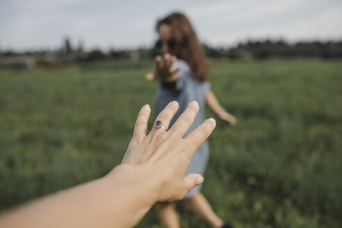 Hand reaching out for woman on a field - KMKF00563