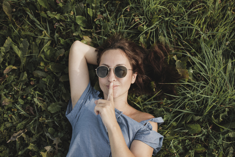 Portrait of smiling woman wearing sunglasses lying in grass stock photo