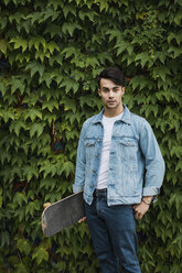 Portrait of young man carrying skateboard - MAUF01691