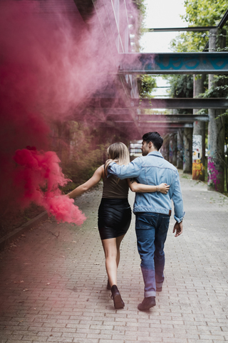Junges Paar mit Rauchfackel beim Spaziergang im Freien, lizenzfreies Stockfoto