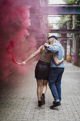 Young couple with smoke torch walking outdoors - MAUF01698