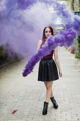Young woman holding smoke torch outdoors - MAUF01702