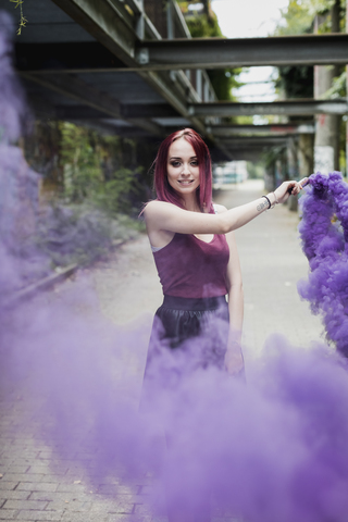 Junge Frau hält Rauchfackel im Freien, lizenzfreies Stockfoto