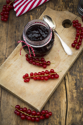 Marmeladenglas mit Johannisbeergelee und roten Johannisbeeren auf Holzbrett, lizenzfreies Stockfoto