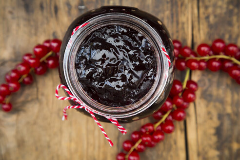 Marmeladenglas mit Johannisbeergelee und roten Johannisbeeren auf Holz - LVF07417