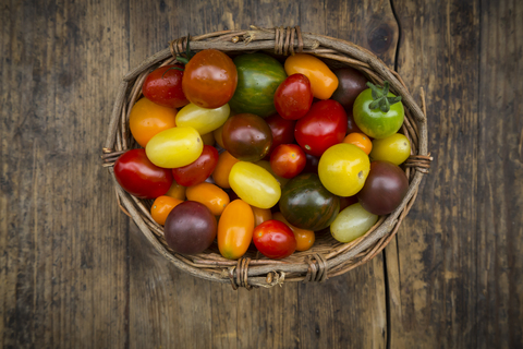 Korb mit Heirloom-Tomaten auf Holz, lizenzfreies Stockfoto