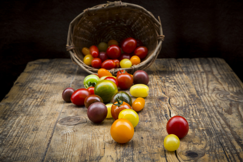 Korb mit Heirloom-Tomaten auf Holz, lizenzfreies Stockfoto