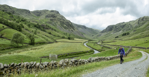 Großbritannien, Lake District, Longsleddale-Tal, reifer Mann geht auf Feldweg in ländlicher Landschaft, lizenzfreies Stockfoto